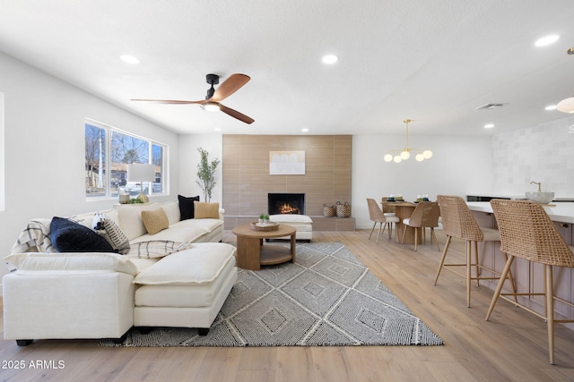 2808 N Steves Blvd, Flagstaff, AZ 86004 - living room featuring a tiled fireplace, recessed lighting, ceiling fan with notable chandelier, and light wood finished floors
