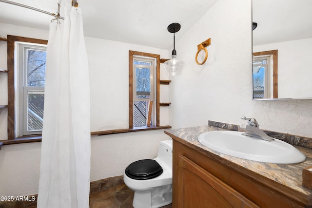 2808 N Steves Blvd, Flagstaff, AZ 86004 - bathroom featuring vanity, toilet, a textured wall, stone finish floor, and baseboards