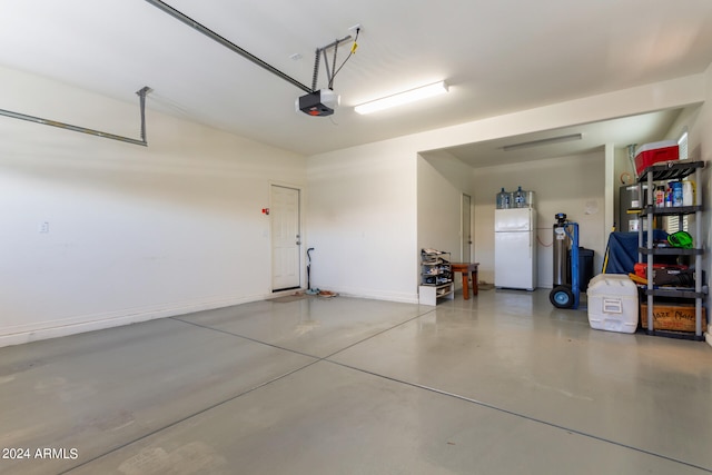 garage featuring white refrigerator and a garage door opener