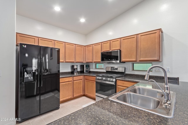 kitchen with appliances with stainless steel finishes, lofted ceiling, sink, and light tile patterned flooring