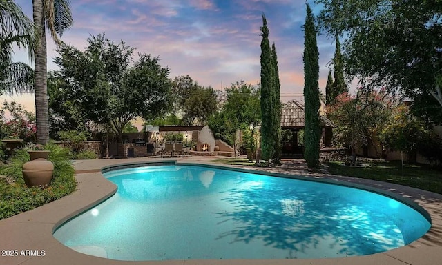 pool at dusk with a patio area