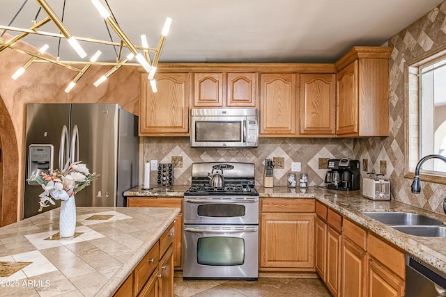 kitchen featuring a wealth of natural light, sink, a chandelier, decorative backsplash, and appliances with stainless steel finishes