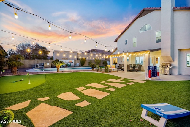 yard at dusk with a patio and a fenced in pool