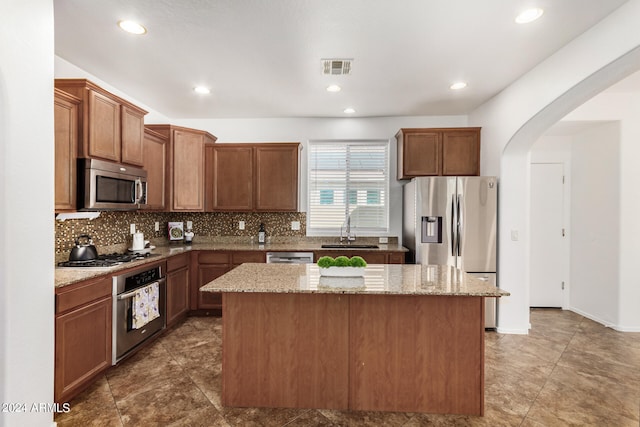 kitchen with sink, a center island, light stone counters, and appliances with stainless steel finishes