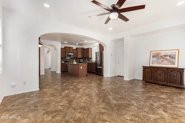 kitchen with decorative backsplash, appliances with stainless steel finishes, a center island, and ceiling fan