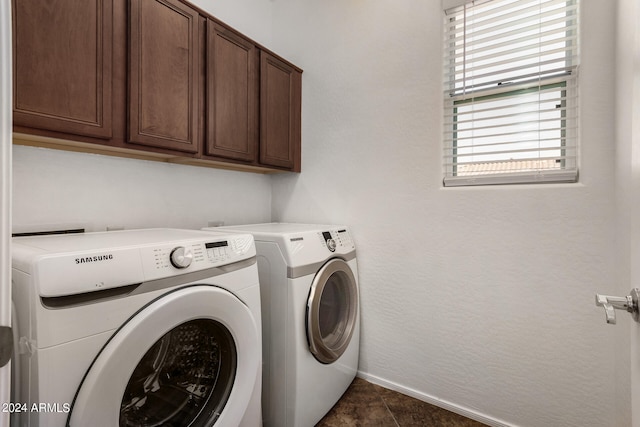 laundry room featuring separate washer and dryer, cabinets, and dark tile patterned flooring