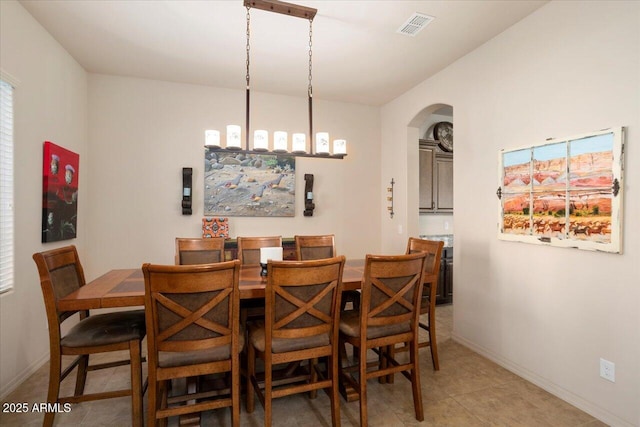 dining area featuring baseboards, visible vents, and arched walkways