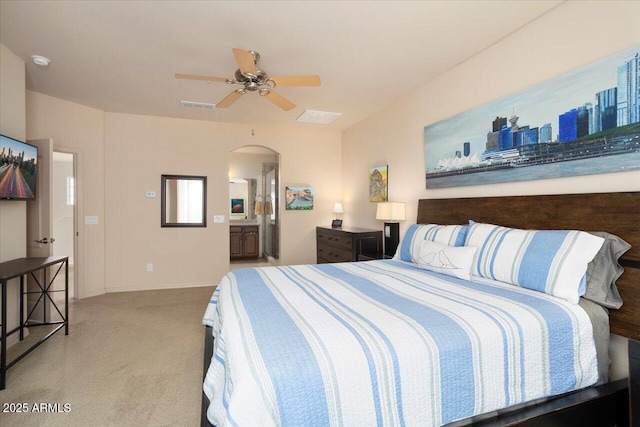 bedroom featuring arched walkways, light colored carpet, visible vents, ensuite bathroom, and a ceiling fan