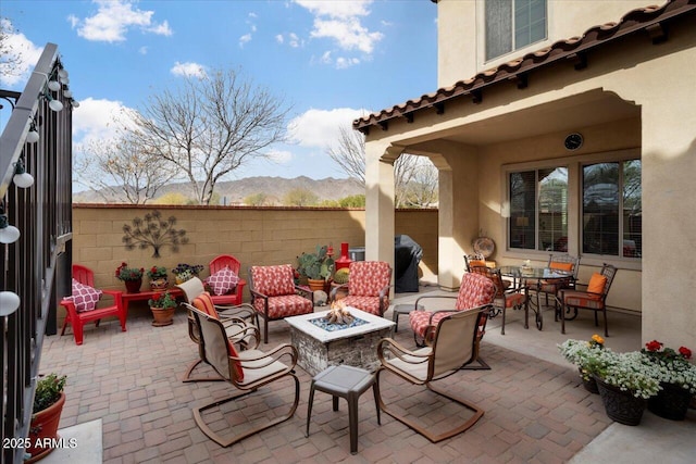 view of patio featuring an outdoor fire pit, grilling area, fence, and a mountain view