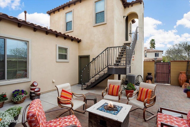 view of patio / terrace featuring a gate, a fire pit, central air condition unit, and stairs