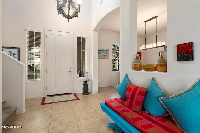 entrance foyer featuring arched walkways, a notable chandelier, baseboards, and light tile patterned floors