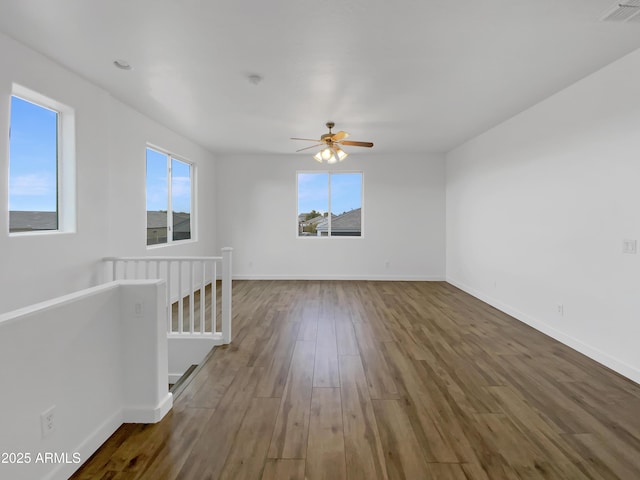 empty room featuring ceiling fan, dark hardwood / wood-style flooring, and a wealth of natural light