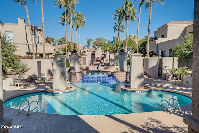 view of swimming pool with pool water feature, a hot tub, and a patio area