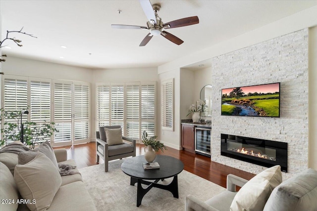 living room with a fireplace, dark hardwood / wood-style flooring, beverage cooler, and ceiling fan