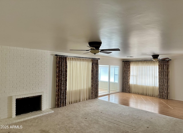 unfurnished living room with ceiling fan, light colored carpet, and a fireplace