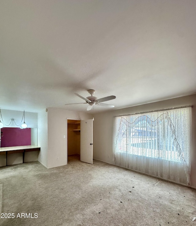 unfurnished bedroom with carpet floors, a walk in closet, a closet, and ceiling fan