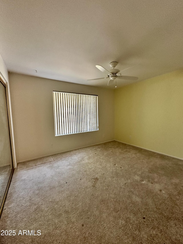 empty room featuring ceiling fan, carpet floors, and a textured ceiling