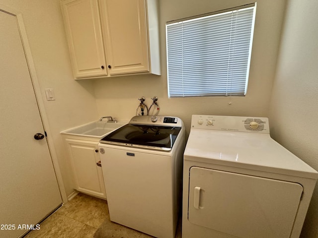 clothes washing area featuring cabinets, sink, and washer and clothes dryer