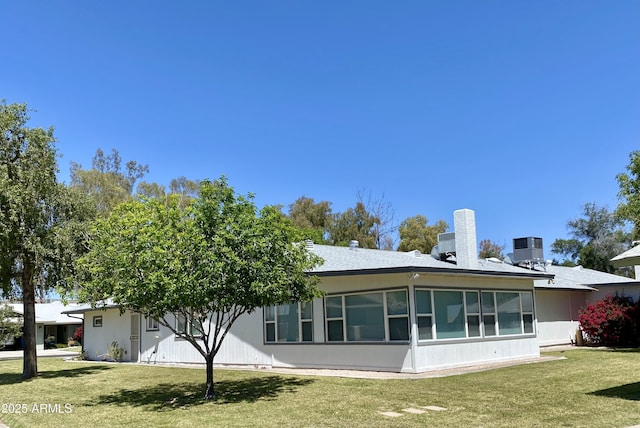 view of front facade featuring a sunroom, cooling unit, and a front lawn