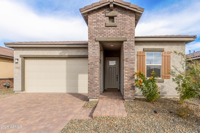 view of front of house featuring a garage, a tiled roof, decorative driveway, and stucco siding