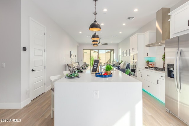 kitchen with stainless steel appliances, visible vents, decorative backsplash, a kitchen island, and wall chimney range hood