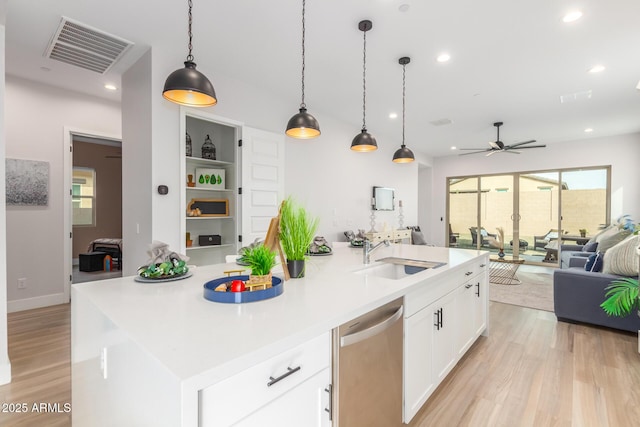 kitchen featuring visible vents, light wood-style floors, open floor plan, a sink, and dishwasher