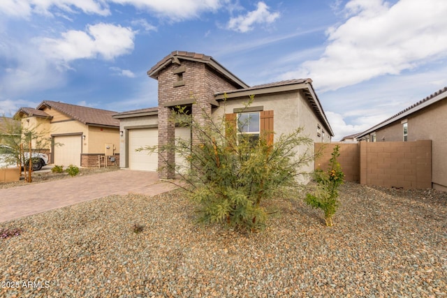 view of front facade with a garage, decorative driveway, fence, and stucco siding