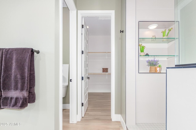 full bathroom with wood finished floors, a spacious closet, and a walk in shower