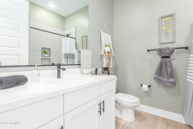 bathroom featuring baseboards, toilet, a shower with curtain, wood finished floors, and vanity