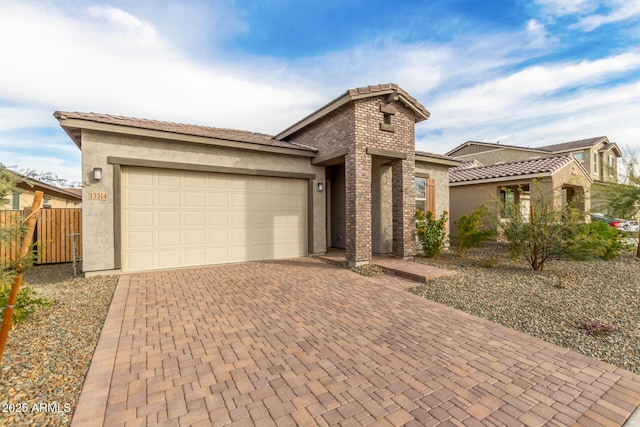 view of front of property with decorative driveway, an attached garage, fence, and stucco siding