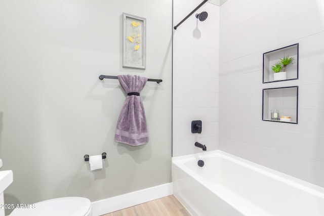 bathroom featuring baseboards, shower / bathing tub combination, toilet, and wood finished floors