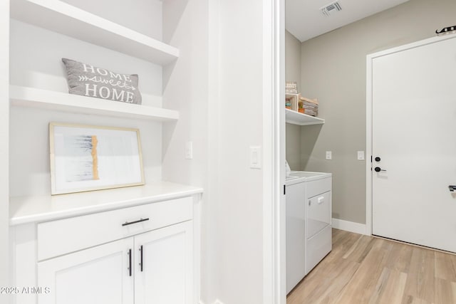 laundry area featuring laundry area, separate washer and dryer, visible vents, and light wood-style floors