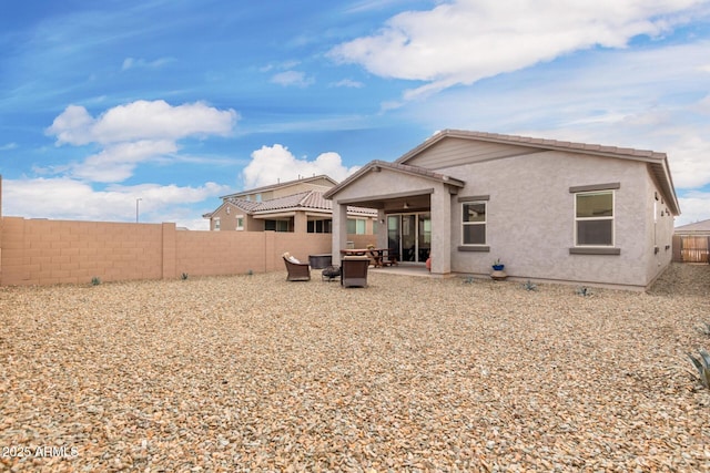 back of house featuring a tiled roof, a patio area, a fenced backyard, and stucco siding