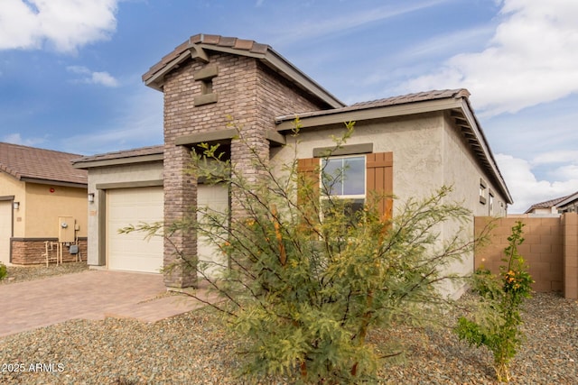 view of front of property featuring decorative driveway, an attached garage, fence, and stucco siding