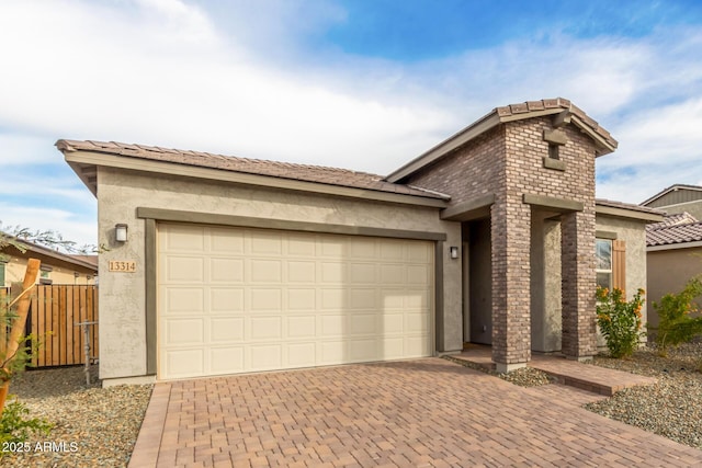 view of front facade featuring decorative driveway, an attached garage, fence, and stucco siding