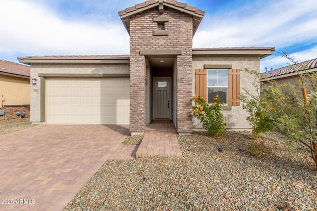 view of front of property featuring stone siding, decorative driveway, an attached garage, and stucco siding