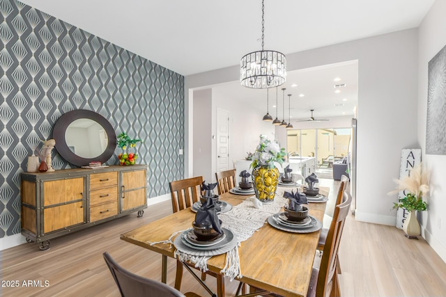 dining space featuring an accent wall, light wood finished floors, baseboards, and wallpapered walls