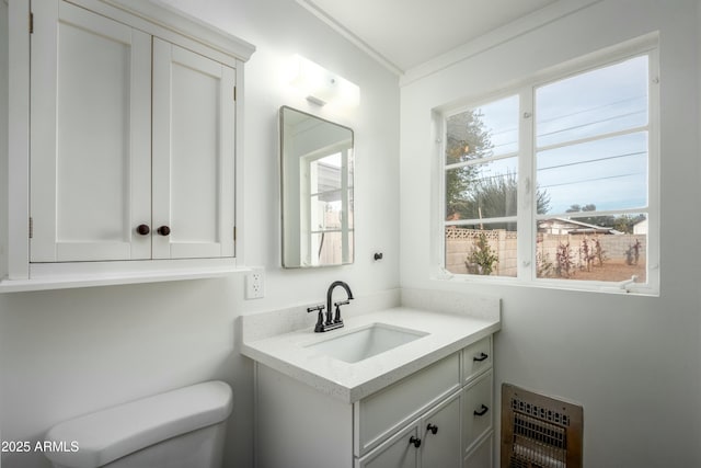 bathroom featuring vanity, a healthy amount of sunlight, ornamental molding, and toilet