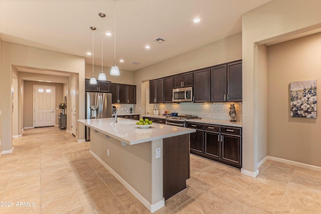 16417 W Piccadilly Rd, Goodyear, AZ 85395 - kitchen featuring stainless steel appliances, a sink, light countertops, an island with sink, and dark brown cabinetry