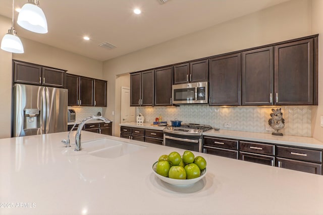 16417 W Piccadilly Rd, Goodyear, AZ 85395 - kitchen featuring stainless steel appliances, dark brown cabinetry, light countertops, a sink, and pendant lighting