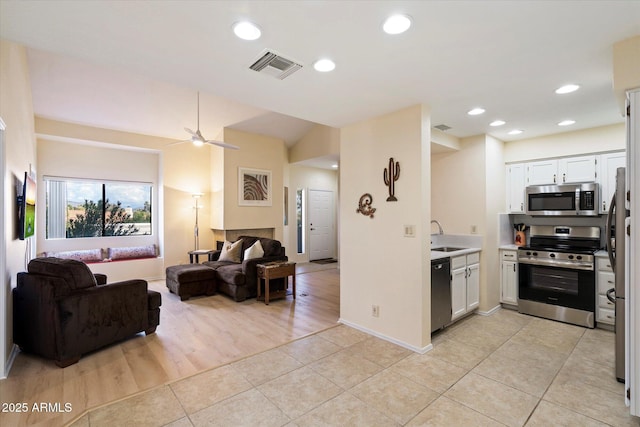 kitchen featuring white cabinetry, sink, light tile patterned floors, ceiling fan, and stainless steel appliances