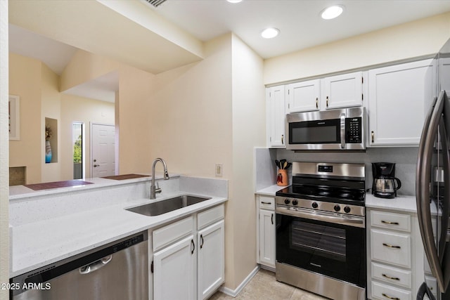 kitchen featuring sink, light tile patterned floors, appliances with stainless steel finishes, white cabinets, and kitchen peninsula