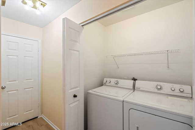 clothes washing area with washer and dryer and light wood-type flooring