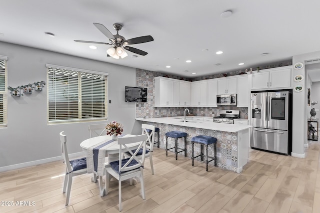 kitchen with white cabinetry, appliances with stainless steel finishes, a kitchen bar, and sink