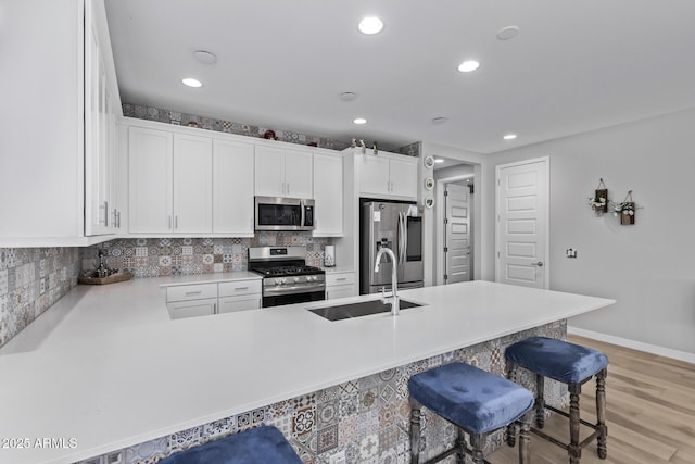 kitchen with sink, a breakfast bar, white cabinetry, stainless steel appliances, and kitchen peninsula