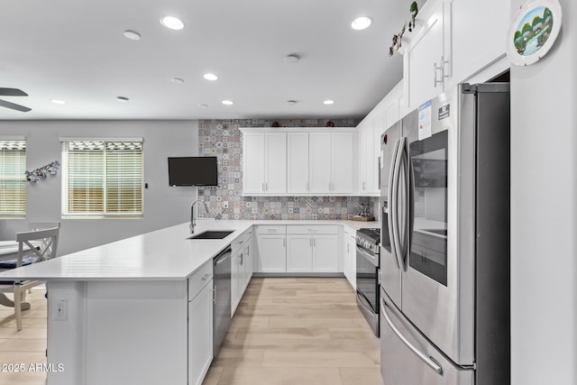 kitchen with sink, appliances with stainless steel finishes, white cabinets, ceiling fan, and backsplash