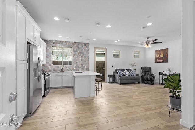 kitchen with sink, white cabinets, a kitchen breakfast bar, a center island, and stainless steel appliances