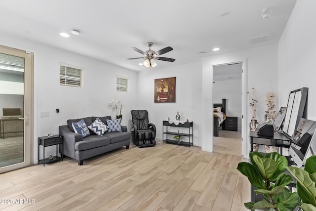 living room with a wealth of natural light, ceiling fan, and light wood-type flooring