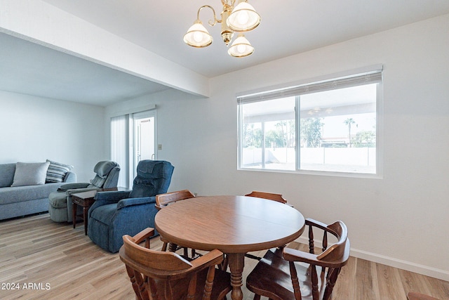dining area featuring an inviting chandelier, baseboards, and light wood-type flooring