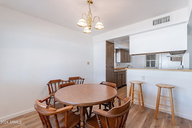 dining area featuring baseboards, a notable chandelier, visible vents, and light wood-type flooring
